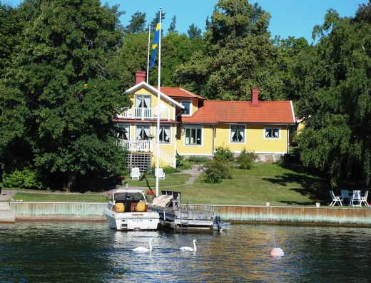 A house in the archipelago with swans passing.   We saw many swans around the islands.