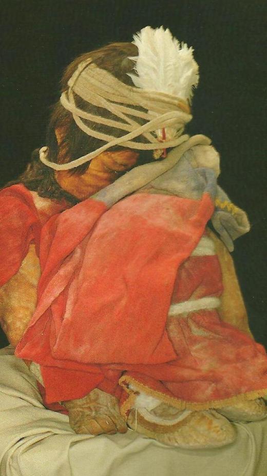 El Nino.  He was about seven years old when he died. The Boy was found seated on a grey tunic with his head facing the rising sun.  As every man of the Inca elite, he wore short hair and a white feather ornament held by a woolen string tied around his head.  Among the varied items that accompanied him was a miniature llama caravan led by finely dressed men.  (From the MAAM brochure)