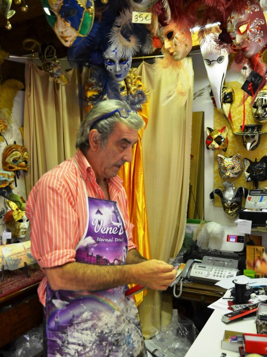 The mask maker wearing his painter's bib of many colors